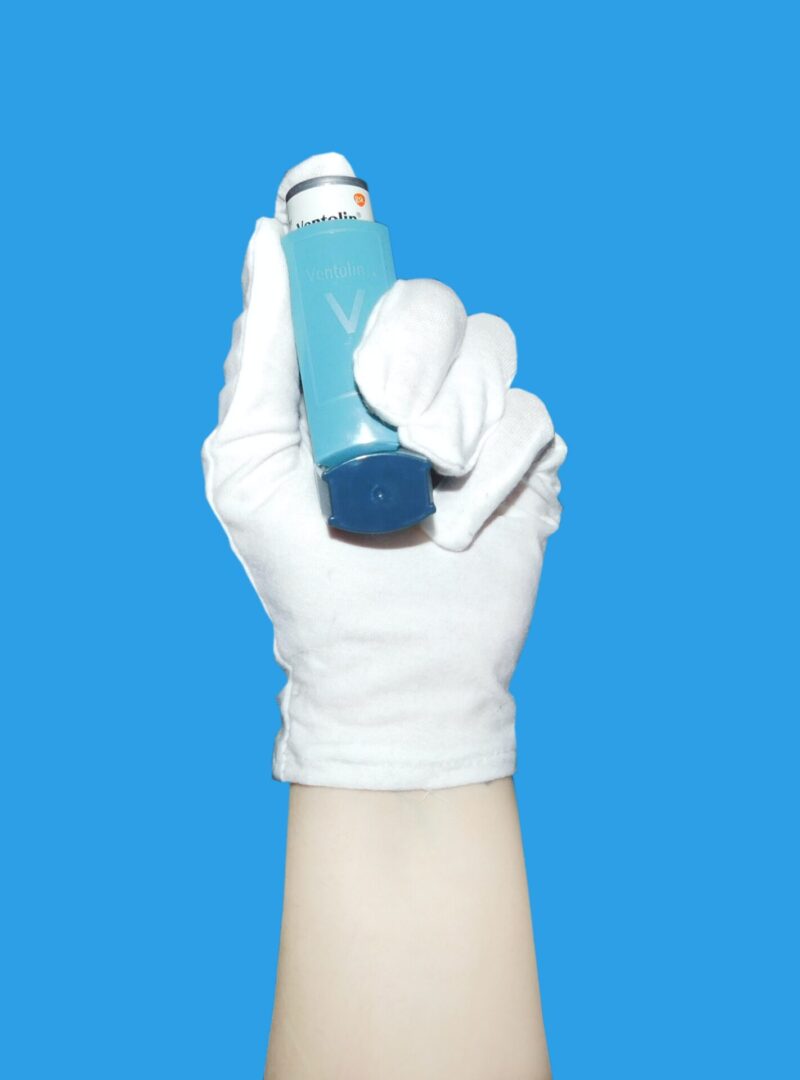 An arm holding an anti-asthma oral spray cannister